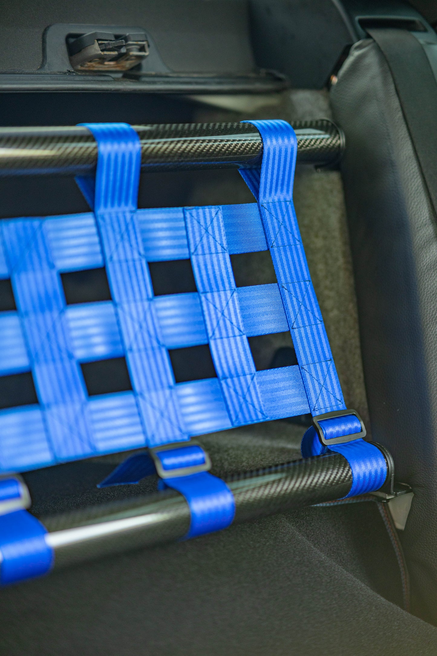 Clubsport-Set für BMW 3 E92 mit Carbon-Strebe und Netz, montiert anstelle der Rücksitzbank für Gewichtsreduzierung und klare Innenraum-Trennung. Ansicht: Detail Carbon und Netz.