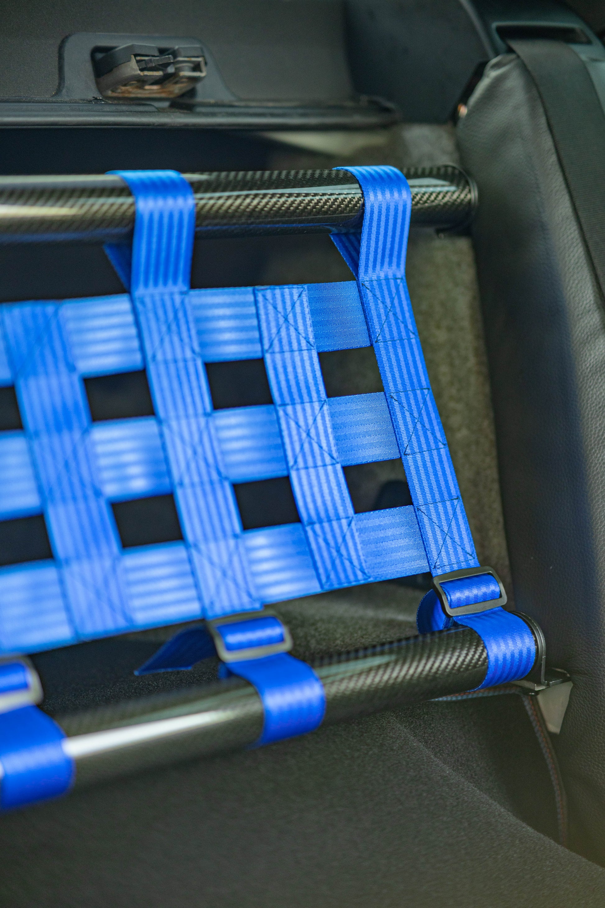 Clubsport-Set für BMW 3 E92 mit Carbon-Strebe und Netz, montiert anstelle der Rücksitzbank für Gewichtsreduzierung und klare Innenraum-Trennung. Ansicht: Detail Carbon und Netz.