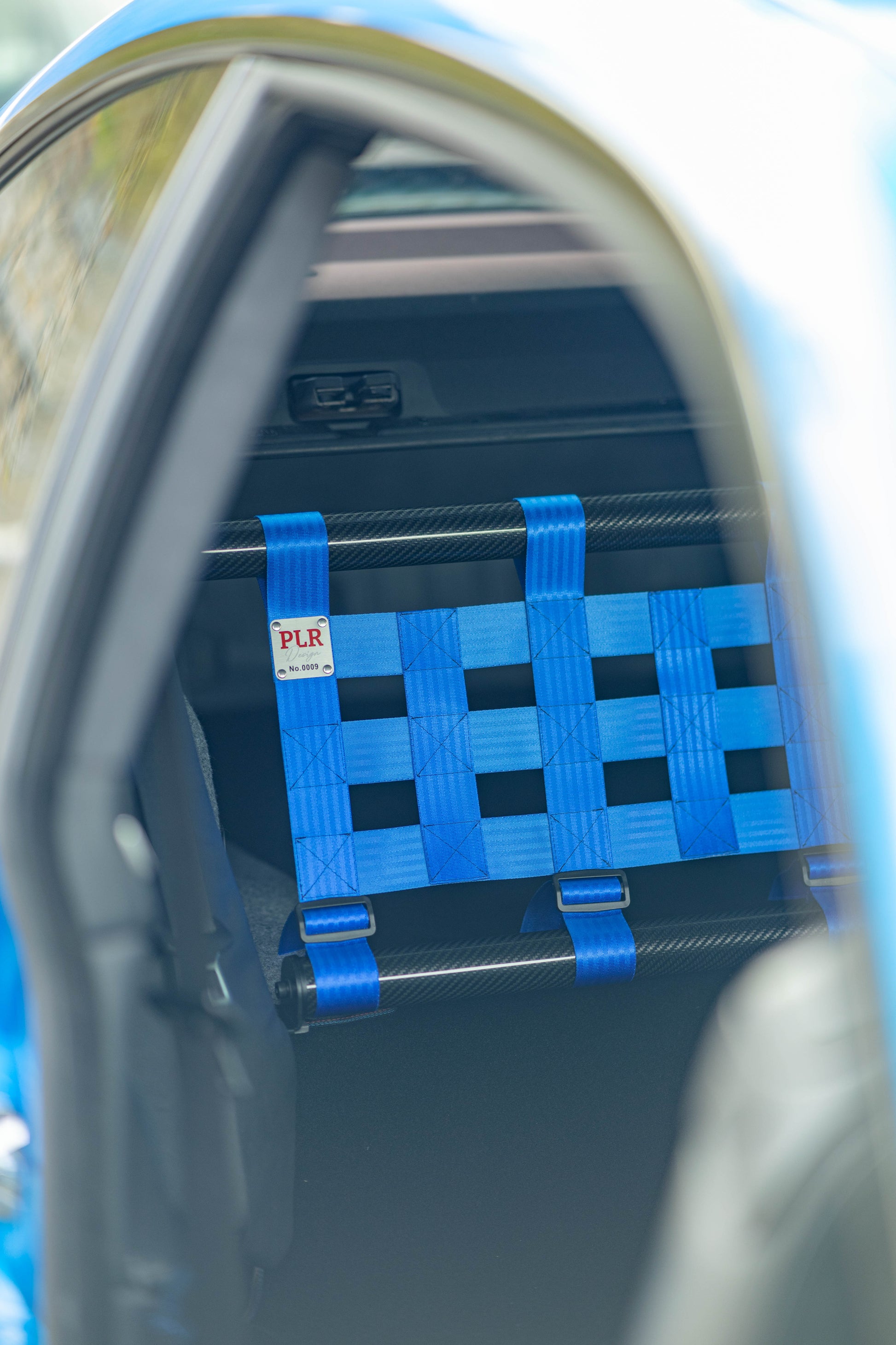 Clubsport-Set für BMW 3 E92 mit Carbon-Strebe und Netz, montiert anstelle der Rücksitzbank für Gewichtsreduzierung und klare Innenraum-Trennung. Ansicht: Beifahrerseite PLR Design.