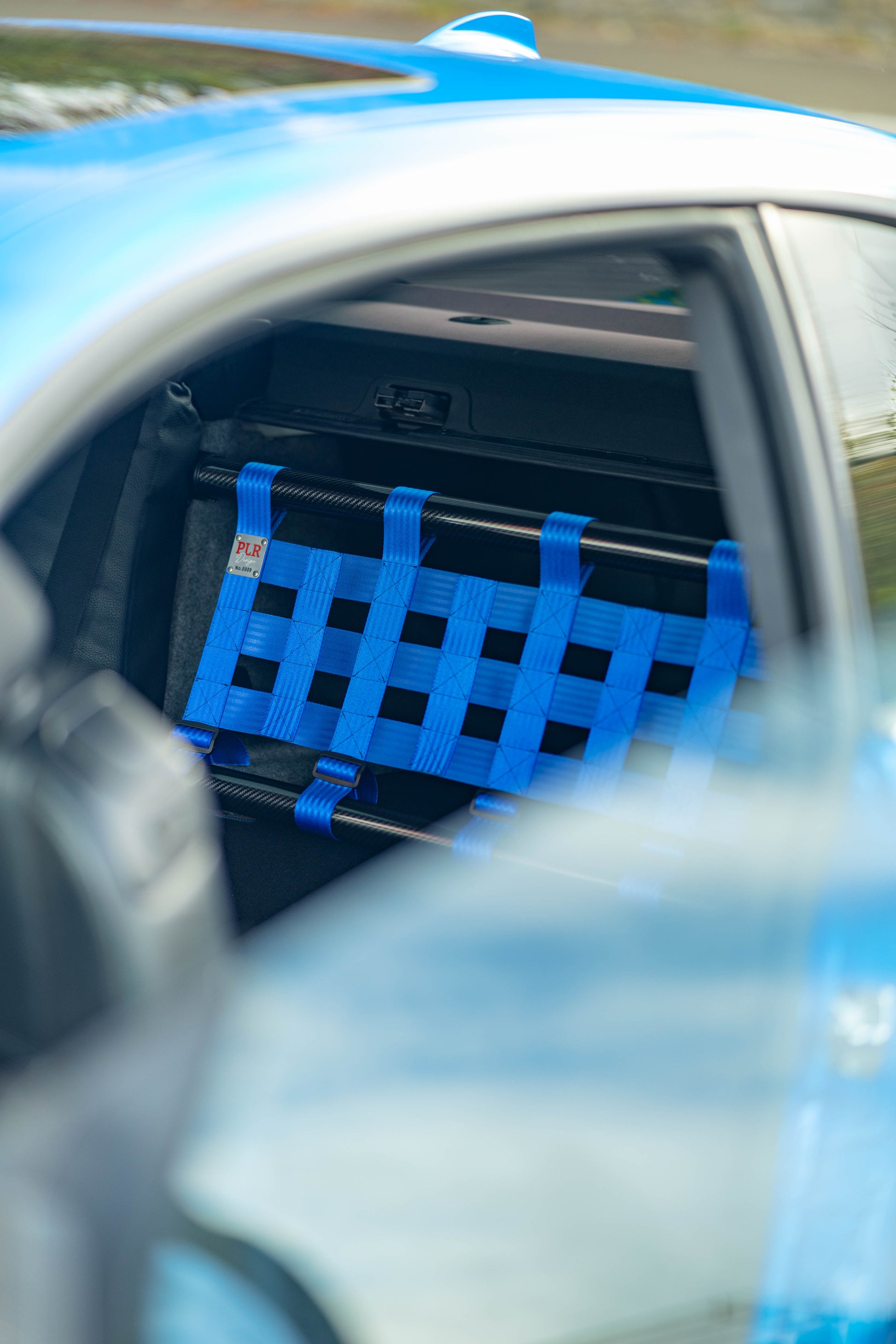 Clubsport-Set für BMW 3 E92 mit Carbon-Strebe und Netz, montiert anstelle der Rücksitzbank für Gewichtsreduzierung und klare Innenraum-Trennung. Ansicht: Cinematic.